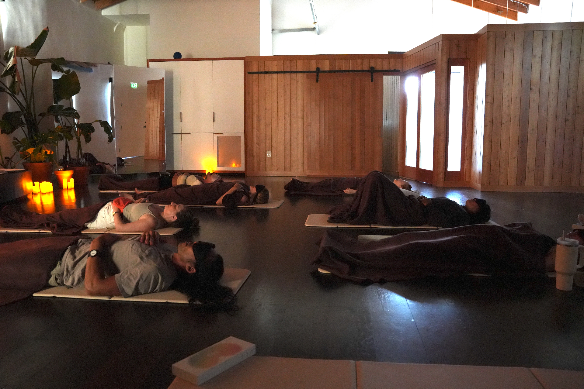 Candlelit breathwork room with participants resting on mats